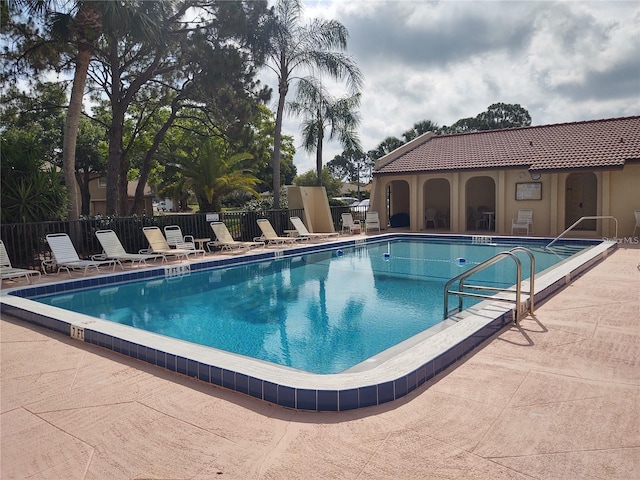 community pool with fence and a patio area