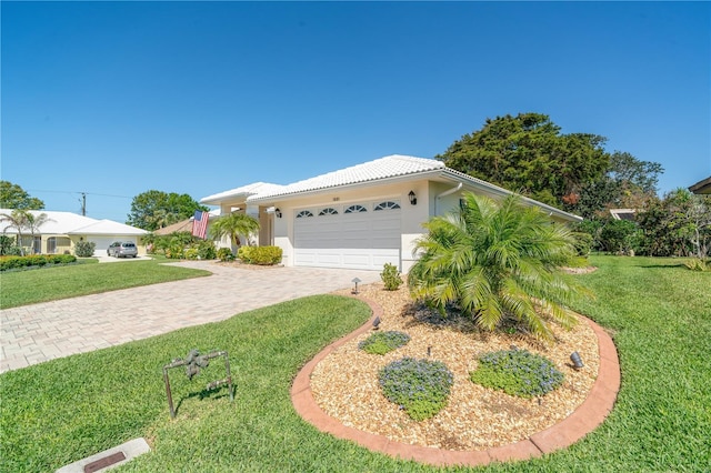 ranch-style house with a tiled roof, a front yard, stucco siding, decorative driveway, and an attached garage