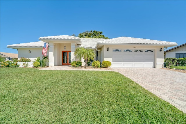 view of front facade featuring stucco siding, french doors, a garage, a tile roof, and decorative driveway