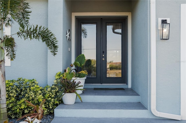 view of exterior entry featuring french doors and stucco siding