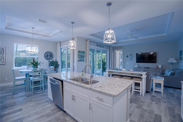 kitchen with visible vents, a kitchen island with sink, a sink, a raised ceiling, and dishwasher