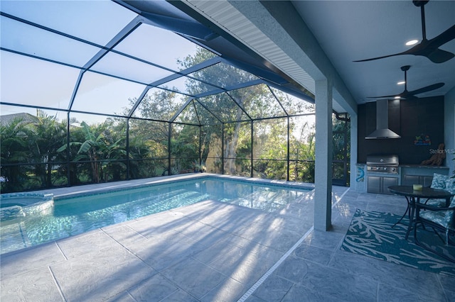 view of pool with grilling area, a patio, an outdoor kitchen, and glass enclosure