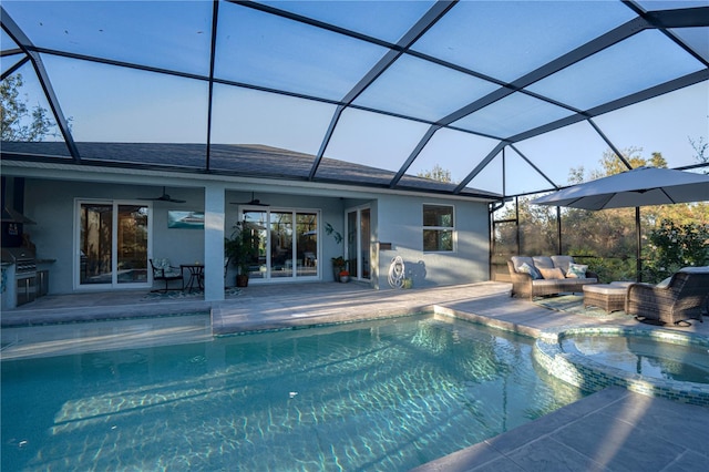 view of swimming pool featuring glass enclosure, a patio, a ceiling fan, and an outdoor hangout area