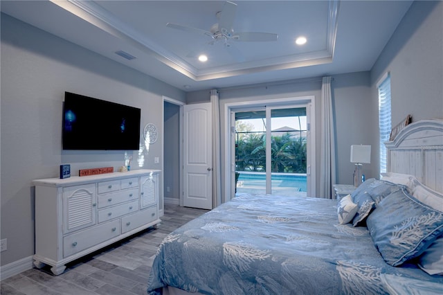 bedroom featuring access to exterior, visible vents, light wood finished floors, baseboards, and a tray ceiling