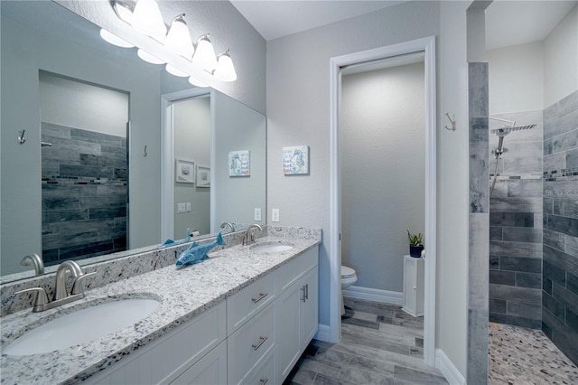 bathroom featuring toilet, a tile shower, and a sink