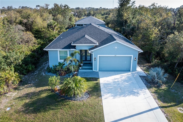 ranch-style house with a shingled roof, a front lawn, stucco siding, driveway, and an attached garage