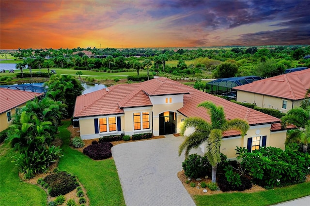 mediterranean / spanish house featuring driveway, a water view, a tile roof, and stucco siding