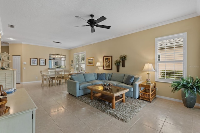 living area featuring crown molding, light tile patterned floors, visible vents, ceiling fan, and baseboards