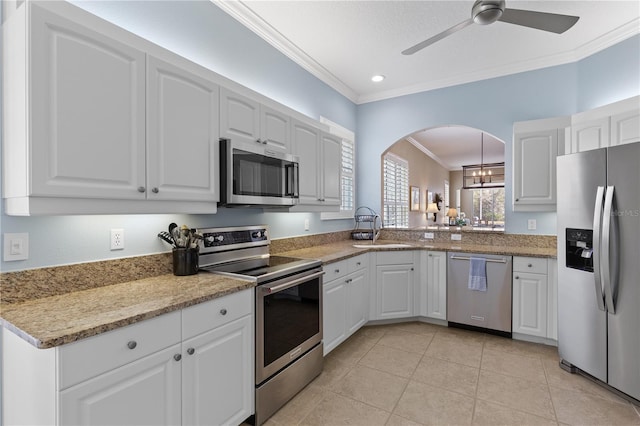 kitchen featuring light tile patterned floors, white cabinets, appliances with stainless steel finishes, crown molding, and a sink