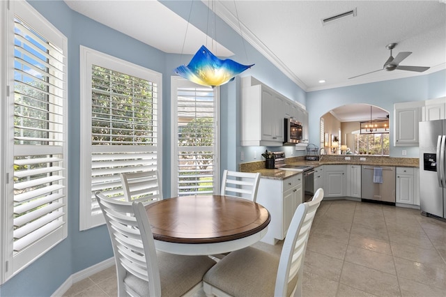 dining space featuring arched walkways, ceiling fan, light tile patterned floors, visible vents, and ornamental molding