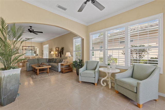 living area featuring visible vents, arched walkways, ceiling fan, ornamental molding, and light tile patterned flooring