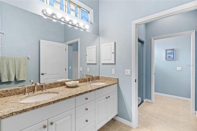 bathroom featuring double vanity, baseboards, a sink, and tile patterned floors