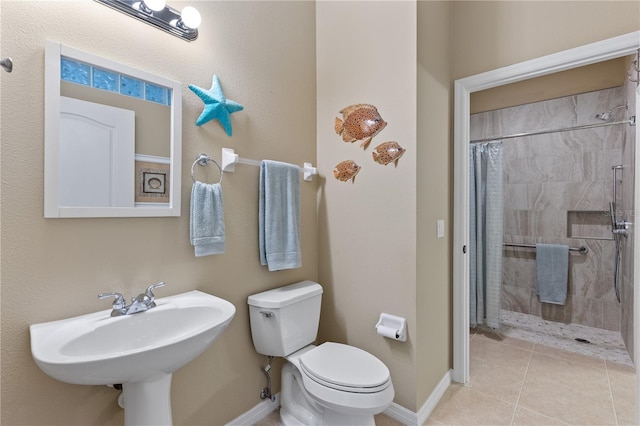 bathroom with tile patterned flooring, baseboards, tiled shower, and toilet