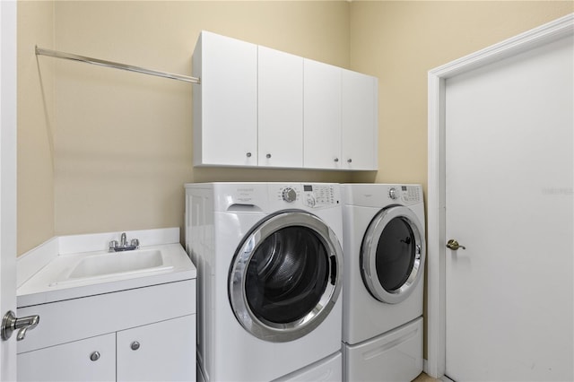 clothes washing area with independent washer and dryer, a sink, and cabinet space