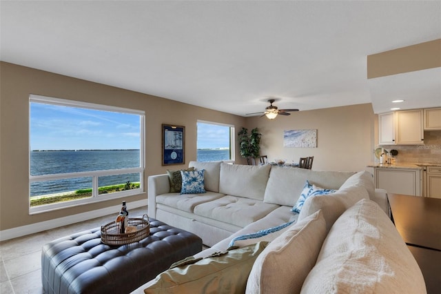 living room featuring a water view, ceiling fan, and baseboards