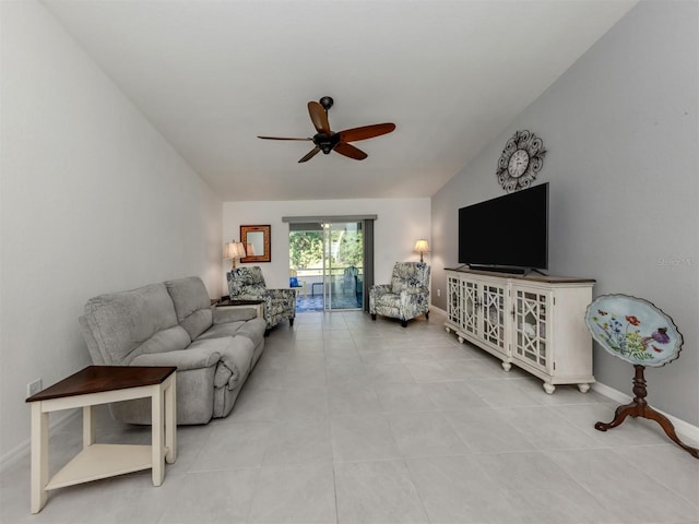 living area with tile patterned floors, baseboards, a ceiling fan, and vaulted ceiling