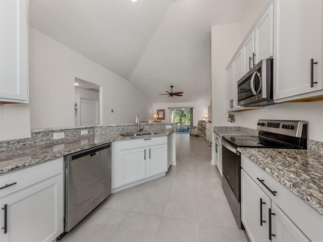 kitchen featuring vaulted ceiling, appliances with stainless steel finishes, a peninsula, light tile patterned flooring, and a sink