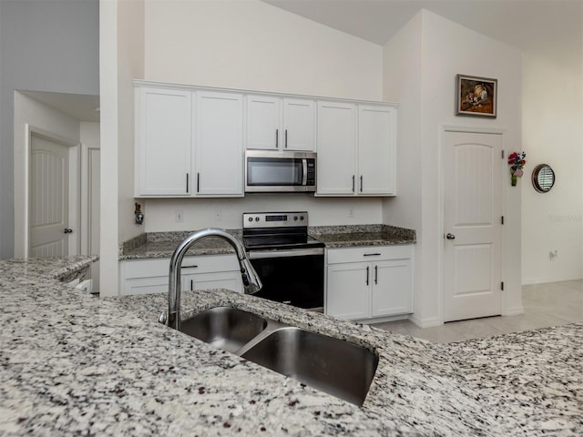 kitchen featuring a sink, light stone countertops, appliances with stainless steel finishes, and white cabinets