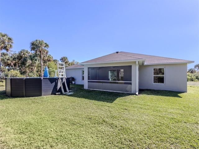 back of house featuring stucco siding, a lawn, a pool, and a sunroom