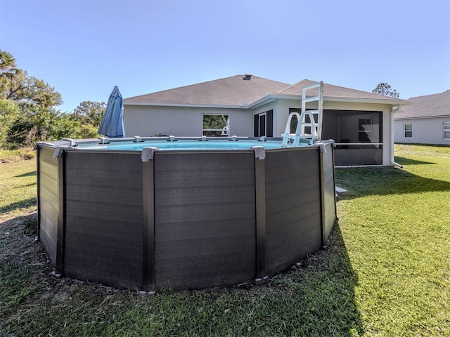 back of house featuring an outdoor pool, a yard, and a sunroom