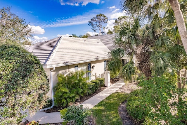 exterior space with a tile roof and stucco siding