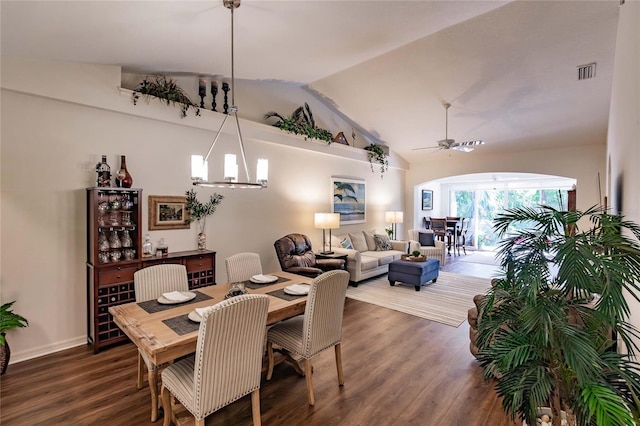 dining space with lofted ceiling, ceiling fan with notable chandelier, wood finished floors, and visible vents