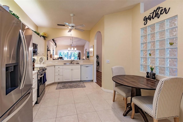 kitchen with light countertops, appliances with stainless steel finishes, white cabinets, a sink, and light tile patterned flooring