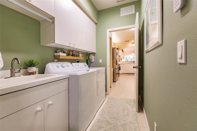 laundry area featuring light tile patterned flooring, washing machine and dryer, a sink, visible vents, and cabinet space