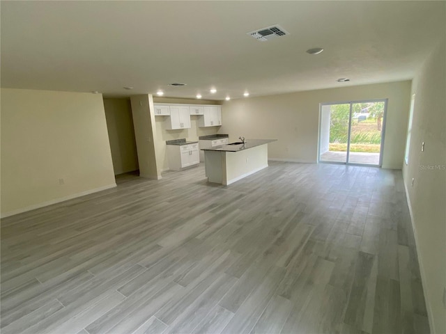 kitchen with open floor plan, light wood-type flooring, visible vents, and white cabinets