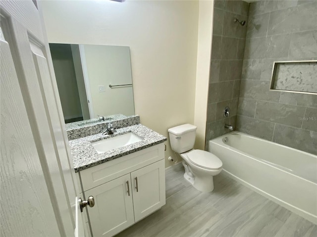 bathroom with baseboards, toilet, wood finished floors, vanity, and shower / washtub combination