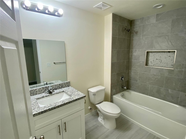 bathroom with baseboards, visible vents, toilet, vanity, and shower / washtub combination