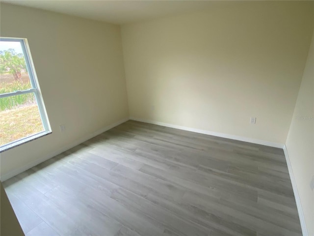 empty room featuring light wood finished floors, plenty of natural light, and baseboards