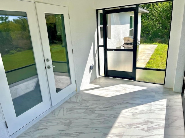 doorway to outside featuring french doors, plenty of natural light, and marble finish floor