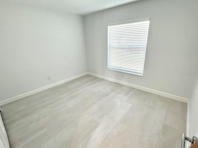 spare room with light wood-style floors and baseboards