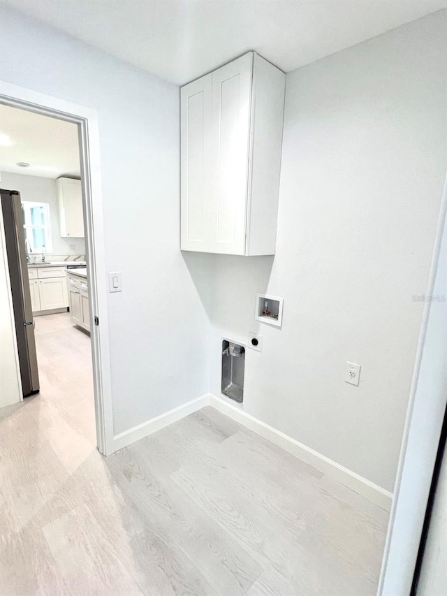 laundry area featuring washer hookup, light wood finished floors, cabinet space, electric dryer hookup, and baseboards