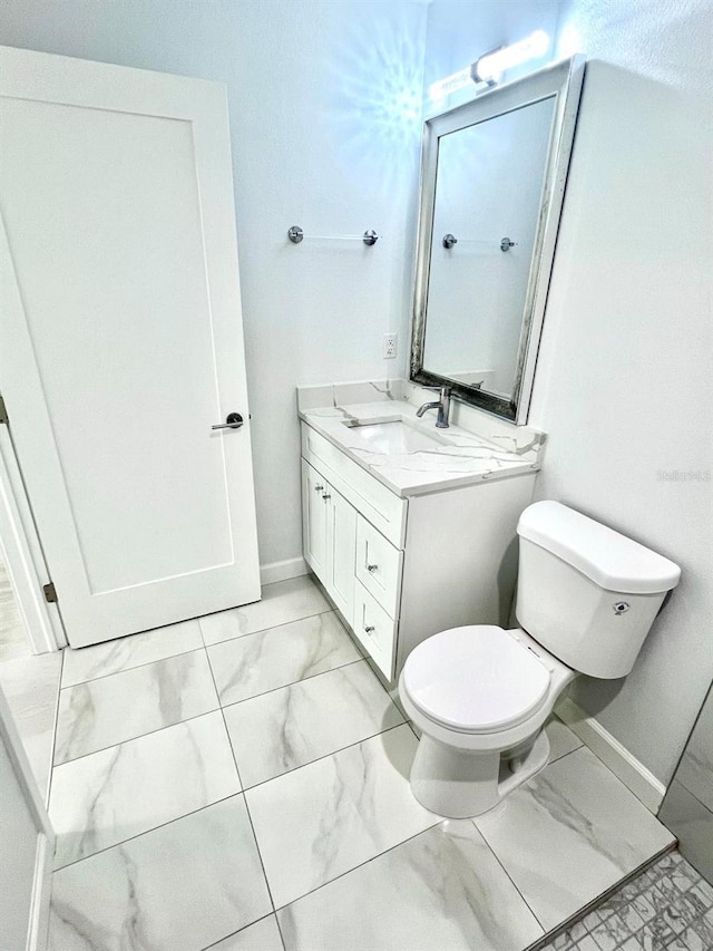 bathroom with toilet, marble finish floor, baseboards, and vanity