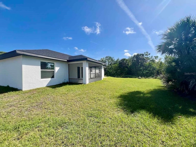 back of property featuring stucco siding and a yard