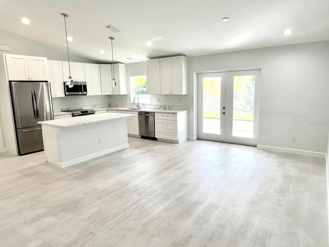 kitchen with a sink, light wood-style floors, french doors, appliances with stainless steel finishes, and a center island