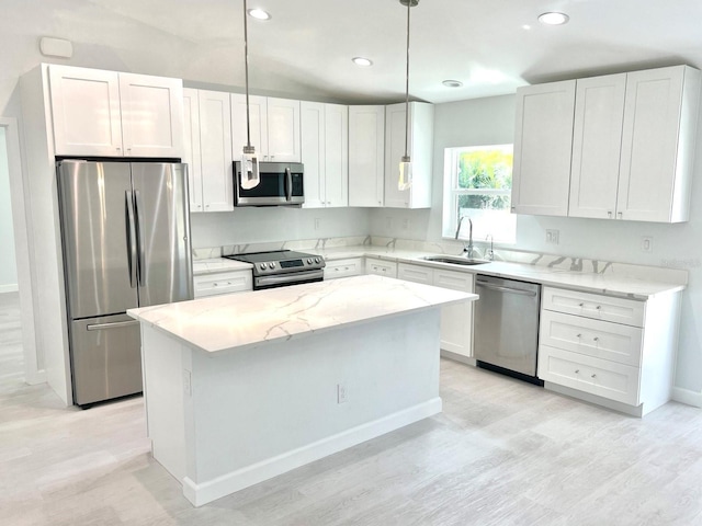 kitchen with a sink, white cabinetry, a center island, appliances with stainless steel finishes, and light stone countertops