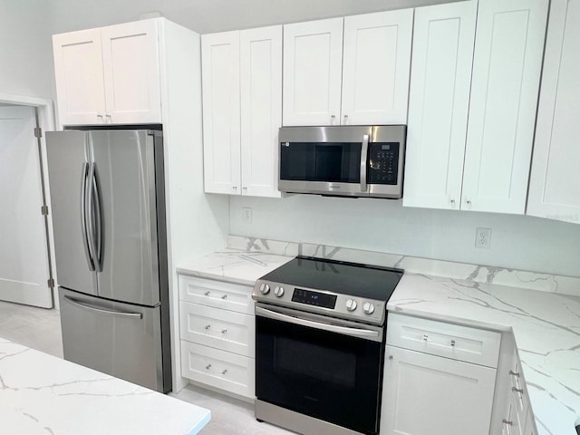 kitchen with appliances with stainless steel finishes, white cabinets, and light stone counters