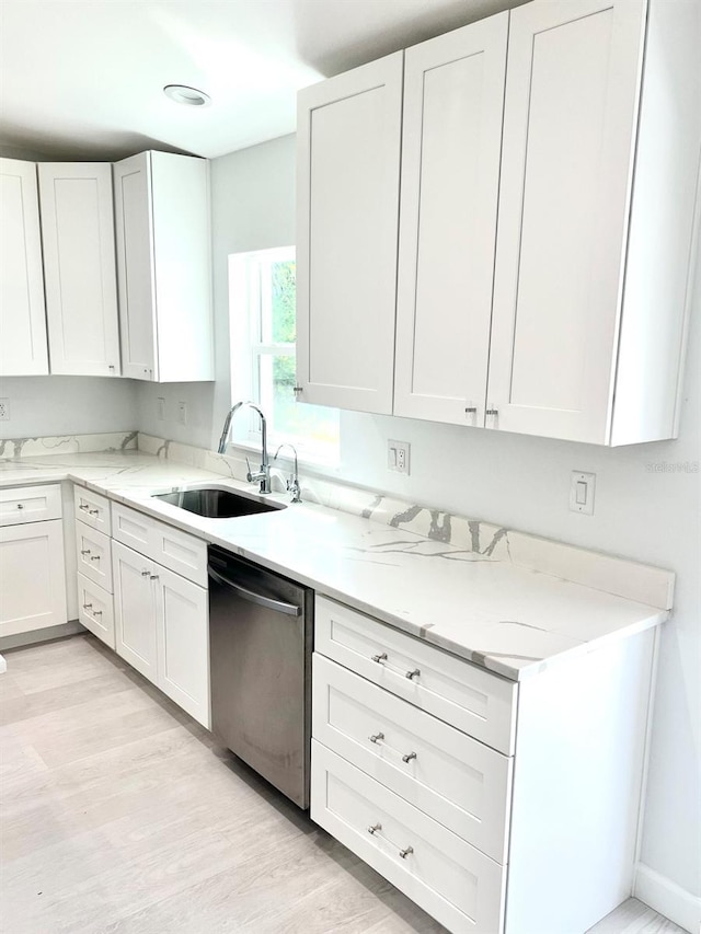 kitchen featuring dishwasher, light wood-style flooring, a sink, and white cabinetry