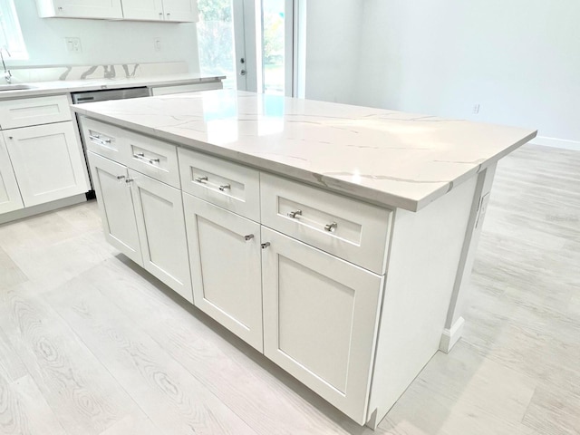 kitchen with light wood-style flooring, white cabinets, and a center island