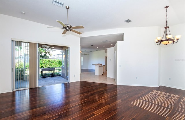 spare room with ceiling fan with notable chandelier, wood finished floors, visible vents, and baseboards