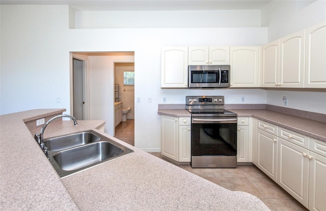 kitchen featuring appliances with stainless steel finishes, light countertops, light tile patterned flooring, and a sink