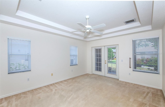 empty room featuring visible vents, a raised ceiling, and french doors