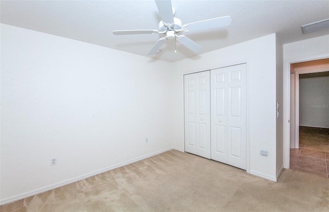 unfurnished bedroom with light carpet, a ceiling fan, visible vents, baseboards, and a closet