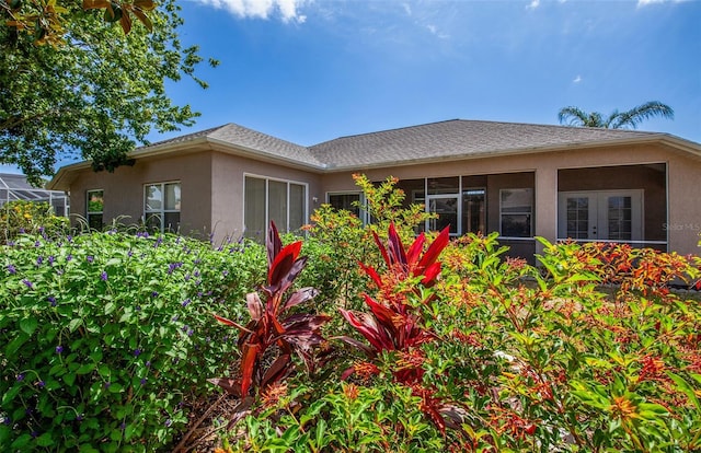 rear view of property with roof with shingles and stucco siding