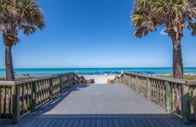 wooden terrace featuring a view of the beach and a water view