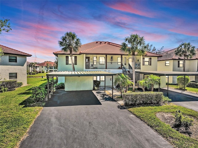 view of front of house featuring stucco siding, a front lawn, driveway, a tile roof, and metal roof