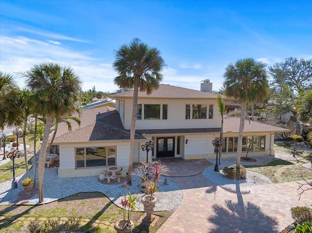 view of front of home with decorative driveway, a patio, a chimney, and stucco siding